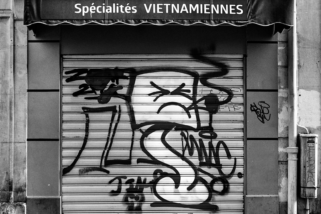 Rideau métallique graffé sous l’enseigne Spécialités vietnamiennes